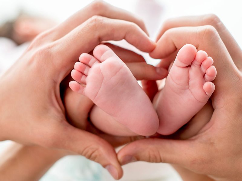 Isän ja äidin kädet muodostavat sydämen vauvan varpaiden ympärille