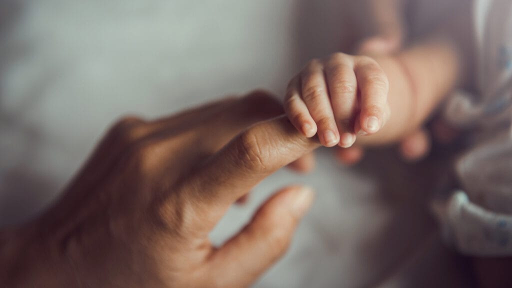 Vastasyntynyt vauva pitää äidin sormesta kiinni.