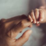 Vastasyntynyt vauva pitää äidin sormesta kiinni.