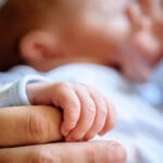 Vastasyntyneen vauvan sormet puristavat äidin sormea.