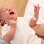 Vastasyntynyt vauva itkee äidin käsivarsilla.