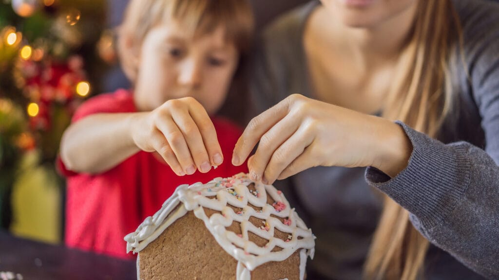 Kouluikäinen lapsi ja äiti leipovat piparkakkutaloa.