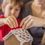 Kouluikäinen lapsi ja äiti leipovat piparkakkutaloa.